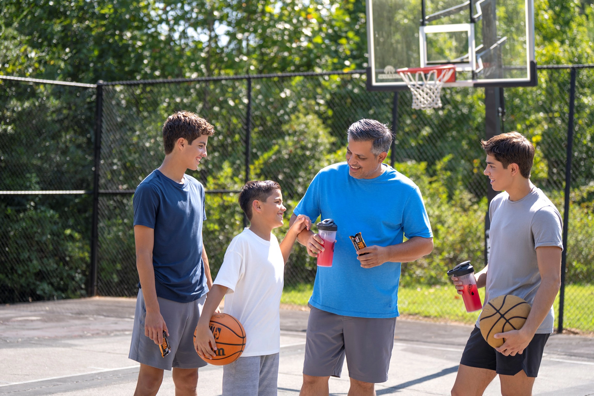 A father and his three sons standing on a basketball court.