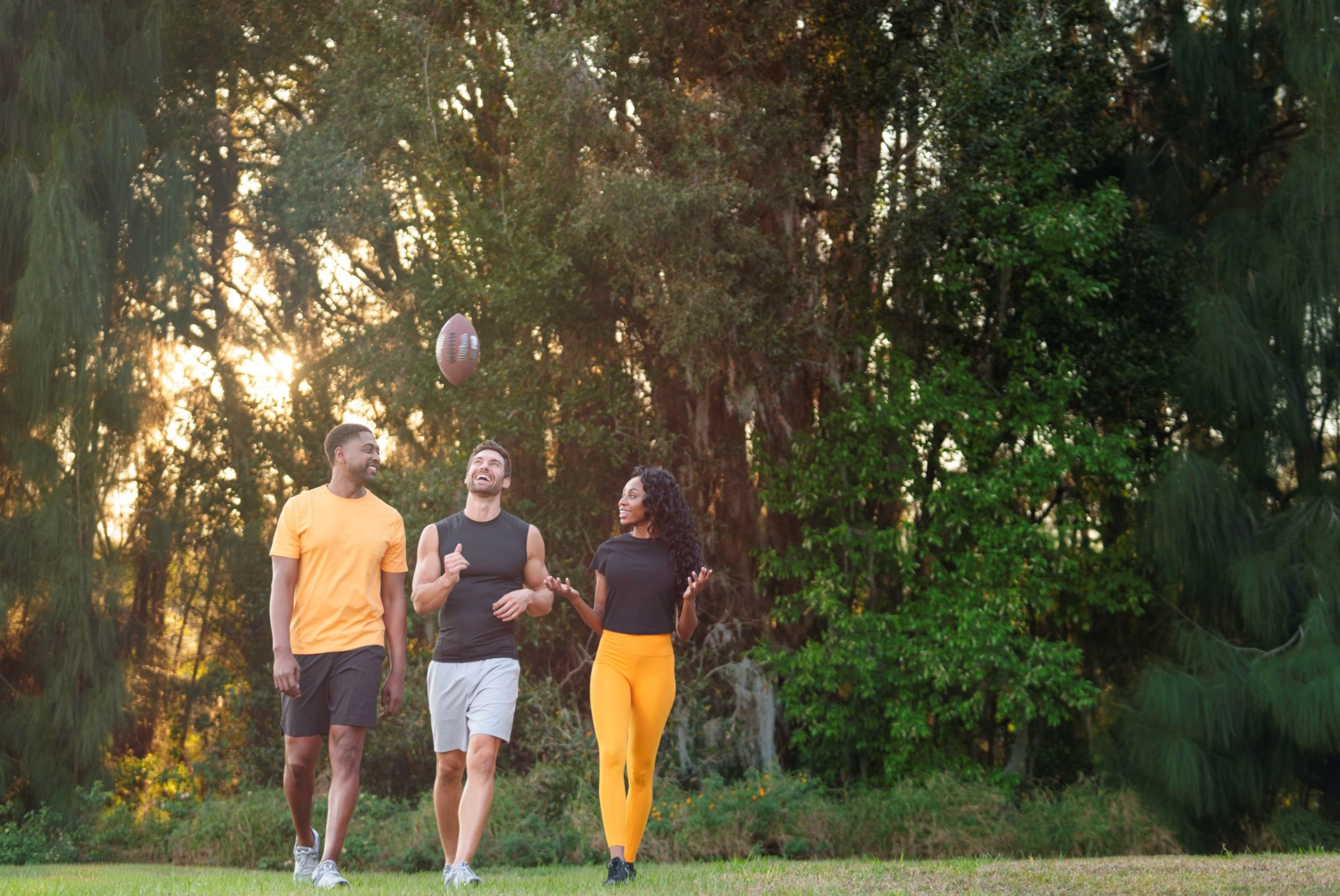 Three people in athletic clothing walking through a park.